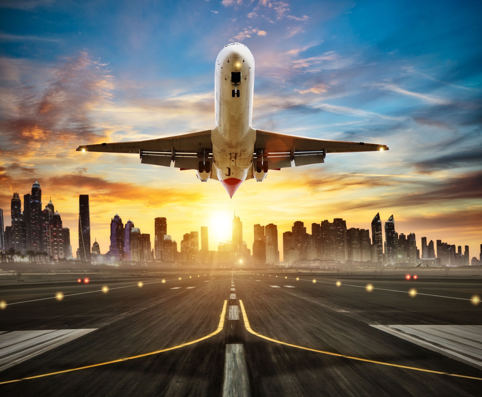 Landing commercial airplane at the runway, modern city on background