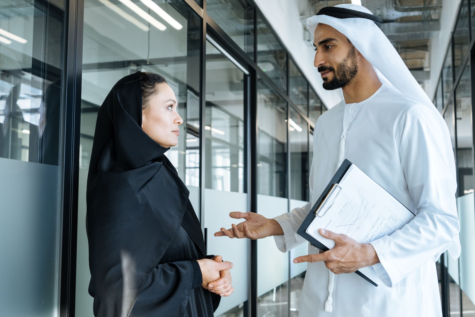 handsome man and woman with traditional clothes working in an office of Dubai